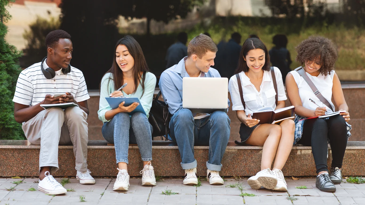 Internationale Gruppe von Studierenden lernt gemeinsam auf einem Campus.
