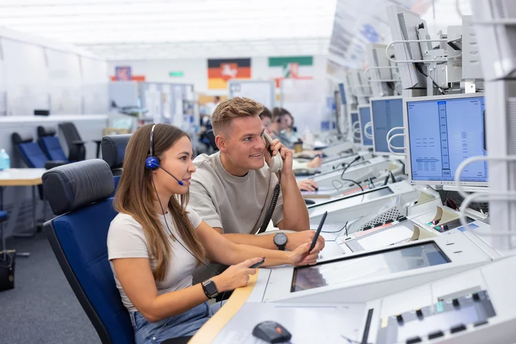Eine Fluglotsin und ein Fluglotse im Center sehen gemeinsam auf einen Bildschirm. 