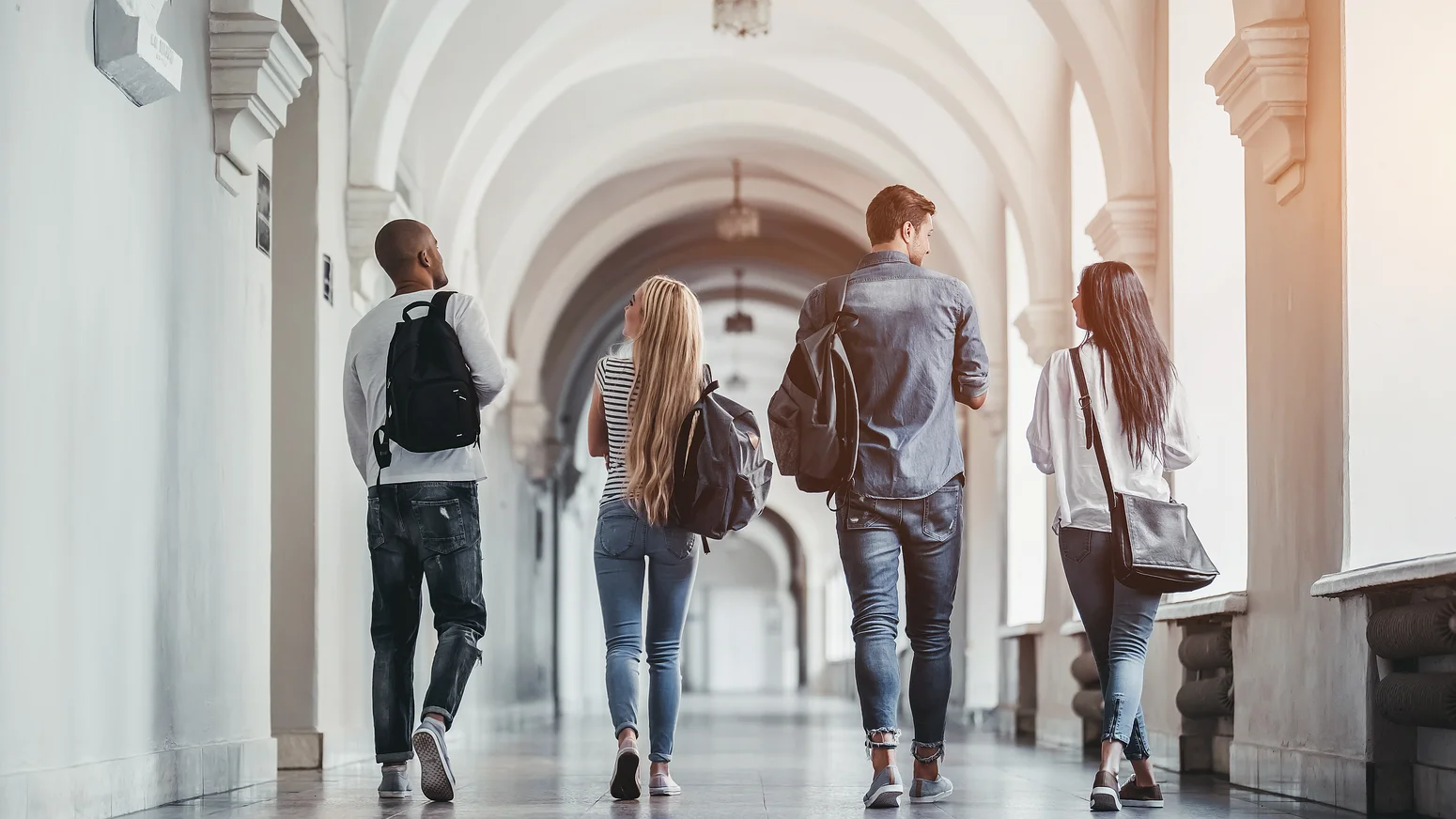 Studierende gehen gemeinsam durch einen Hochschulgang.