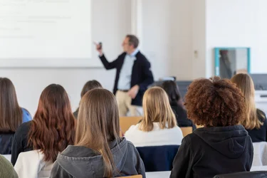 Zwei Studentinnen folgen den Ausführungen des Dozenten.